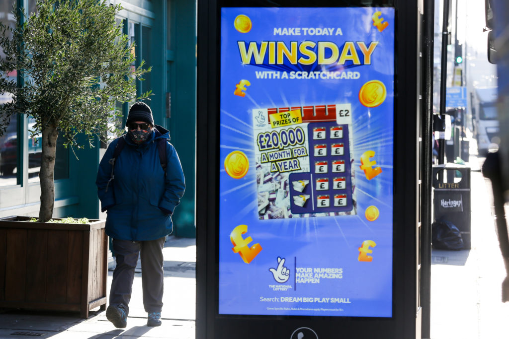A man wearing a face mask walks past the National Lottery's