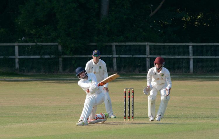 2 men playing cricket on green grass field during daytime