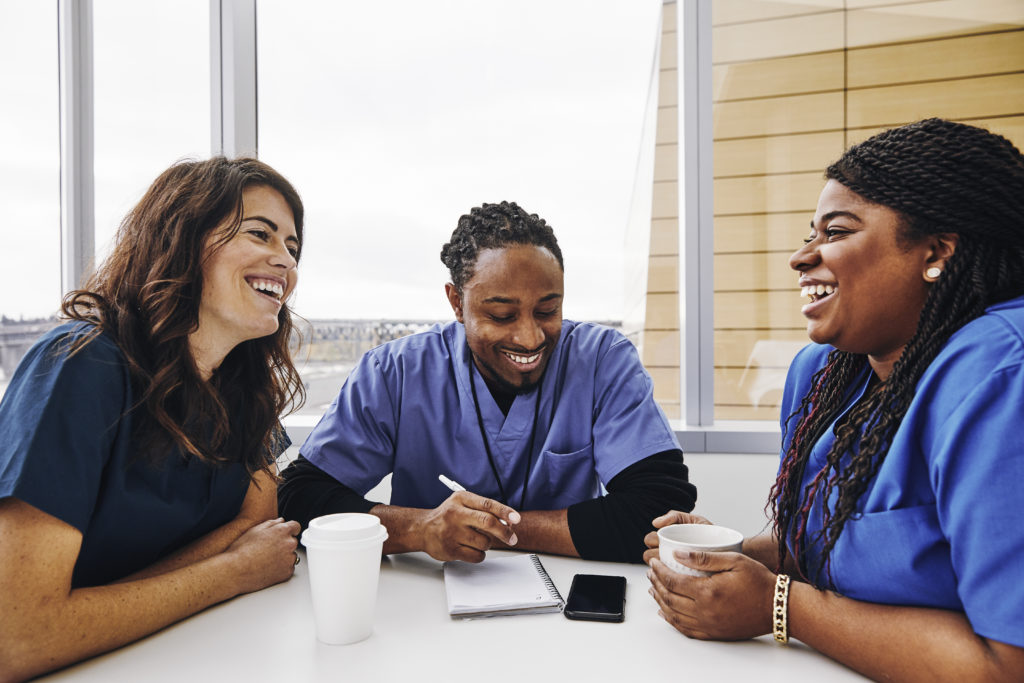Cheerful male and female nurses talking at table in hospital