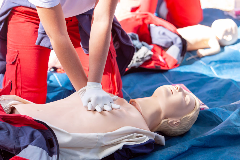Midsection Of Person Practicing Cpr On Dummy Outdoors