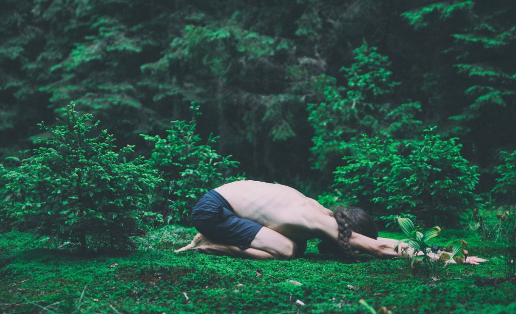 woman in black tank top and pink leggings doing yoga on green grass field during daytime