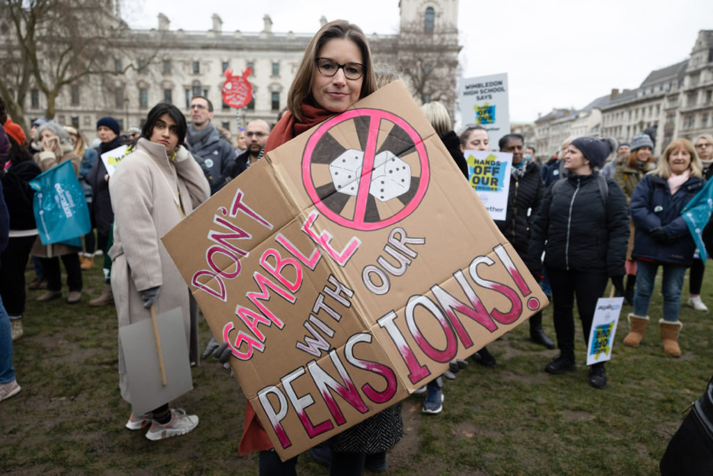 A teacher is seen holding a placard expressing her opinion,