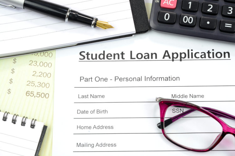 Applying for student loan. Filling up the loan form with calculator, pen, note pad on the desk.