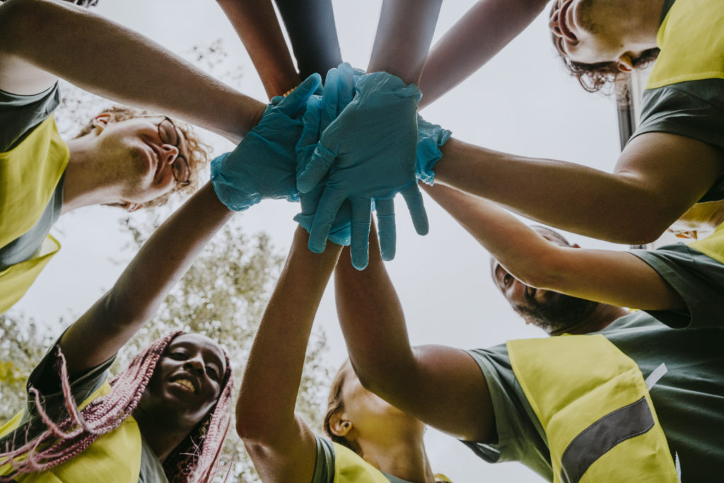 Volunteers wearing gloves bringing hands together