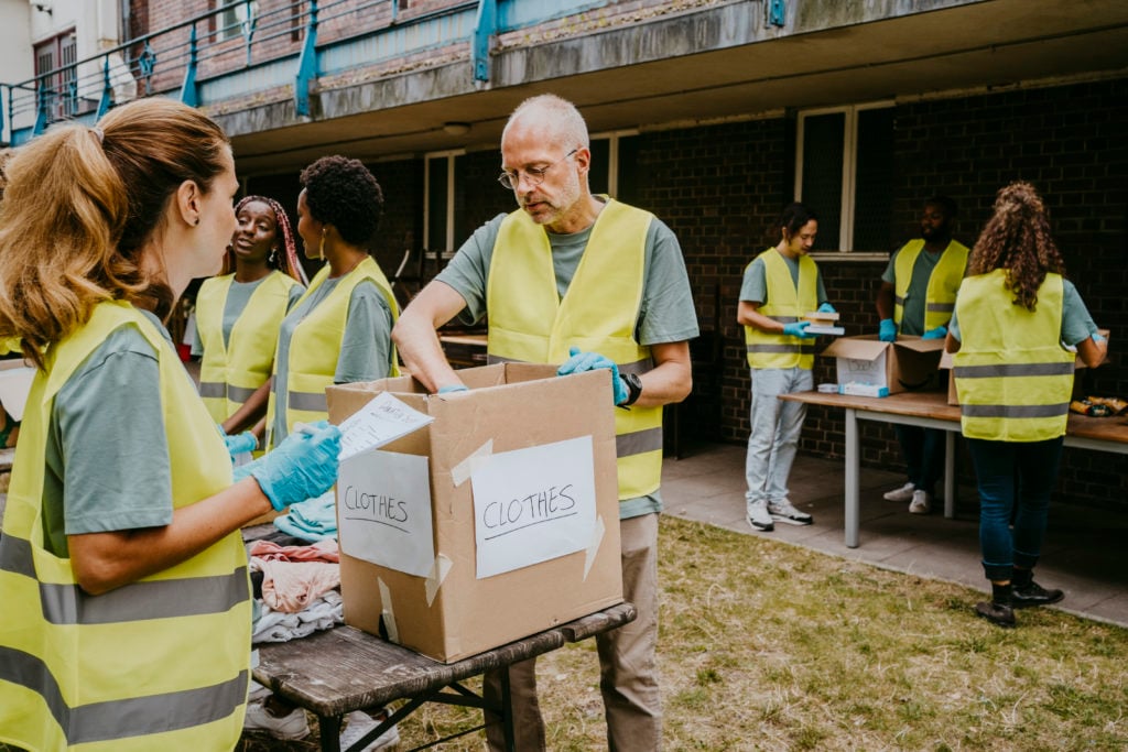 Male and female friends doing teamwork while volunteering in garden