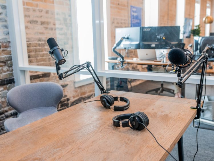 two black podcasts headphones on brown wooden table