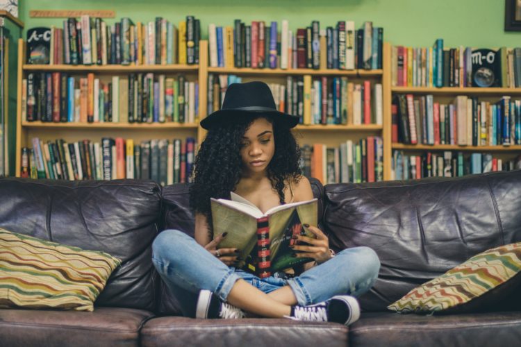 woman reading a book while sitting on black leather 3-seat couch