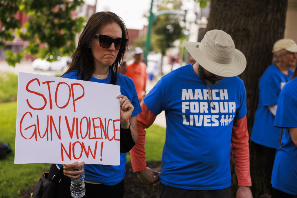A woman holds a placard that says Stop Gun Violence Now