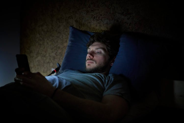 Man texting in bed