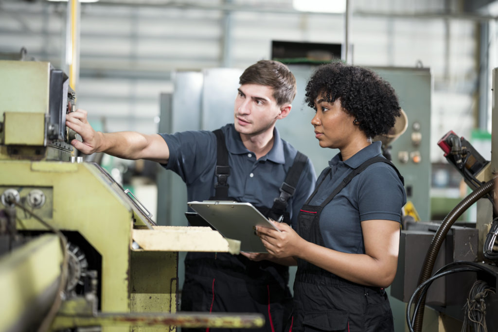 Change Management Keeps Operations Running Smoothly In the Manufacturing Process. Multiracial Group of Engineers are making discussion at a CNC machine about the production process change to improve quality and productivity in the Automobile Industry.