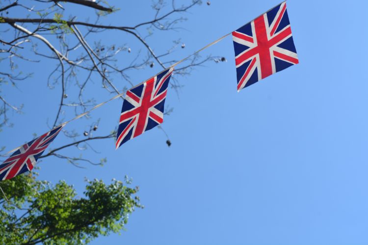 Union Jack flag bunting hanging against a blue summer sky background