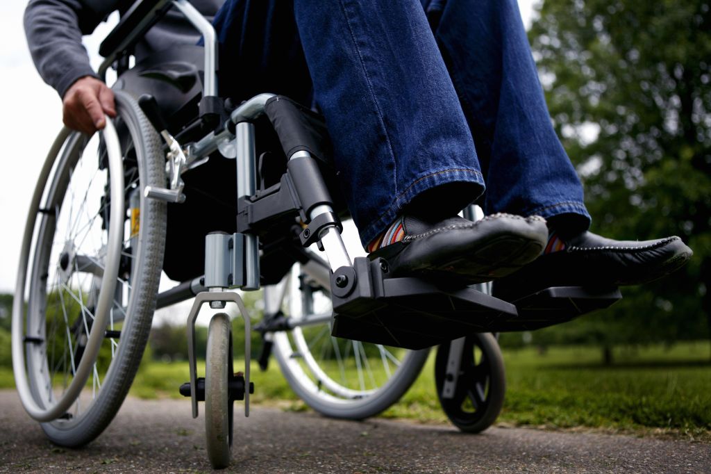 Man in wheelchair on path in park, low section