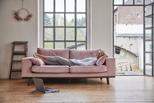 Woman relaxing on sofa in living room at home