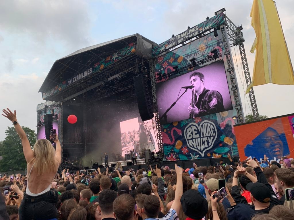 Sam Fender performing on stage as fans sing along.