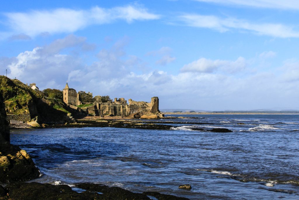 brown rock formation on sea under white clouds and blue sky during daytime