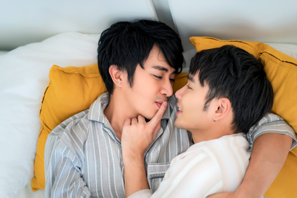 Young Asian gay couple together on bed at home.