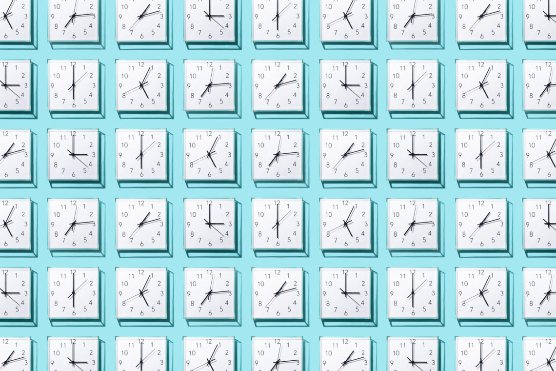 Neatly Arranged White Colored Wall Clocks Displays Different Time on Solid Blue Background.