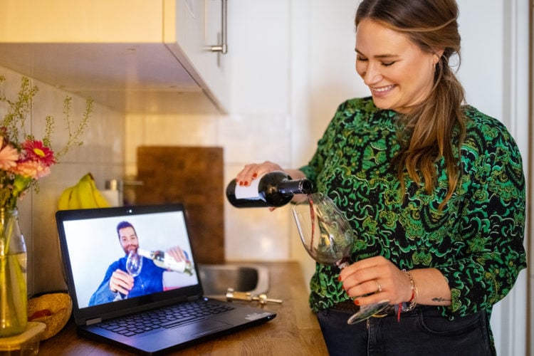 Man and woman filling their wine glass during a video call. Couple in love having a video call.