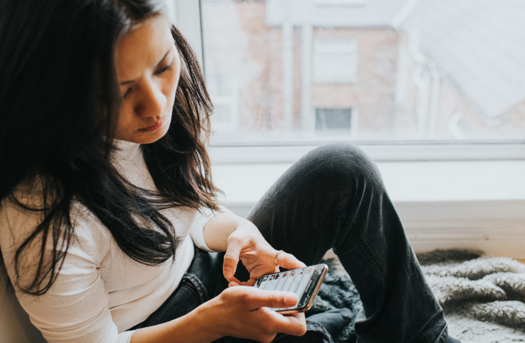 A perplexed woman checks her smart phone
