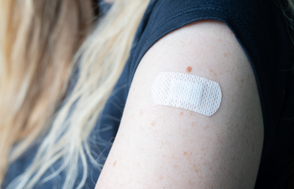 A woman has just been vaccinated against Covid-9. You can see the band-aid on her skin.