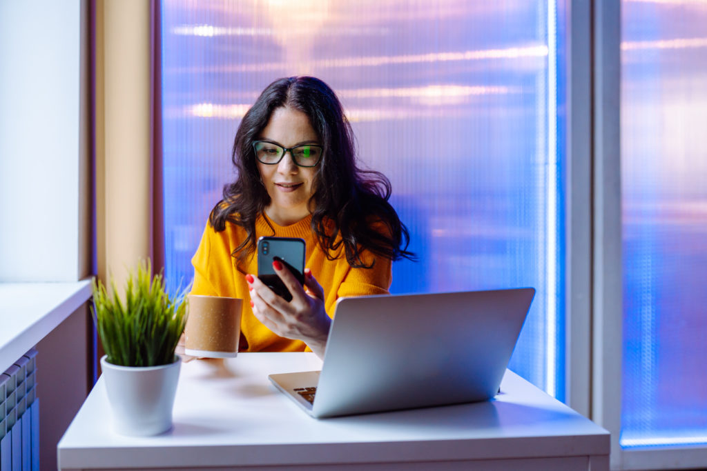 Woman sitting at working place, using smartphone for taking an interview as a recruiter manager