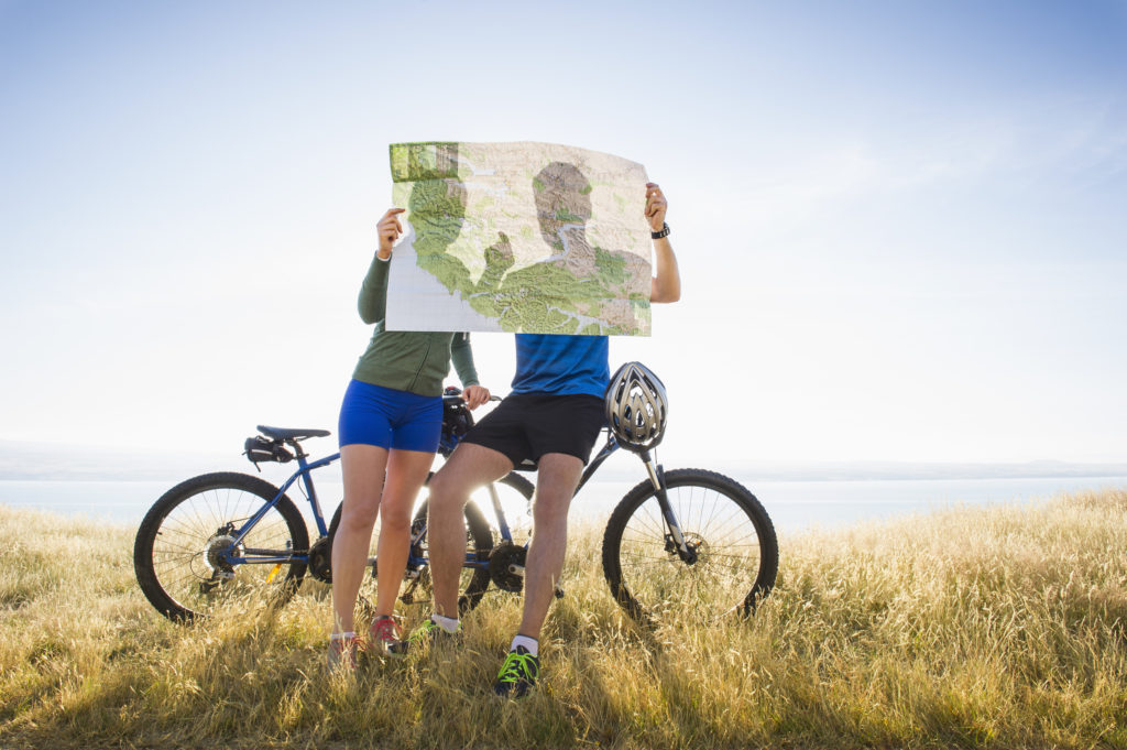 Caucasian couple reading map in rural landscape