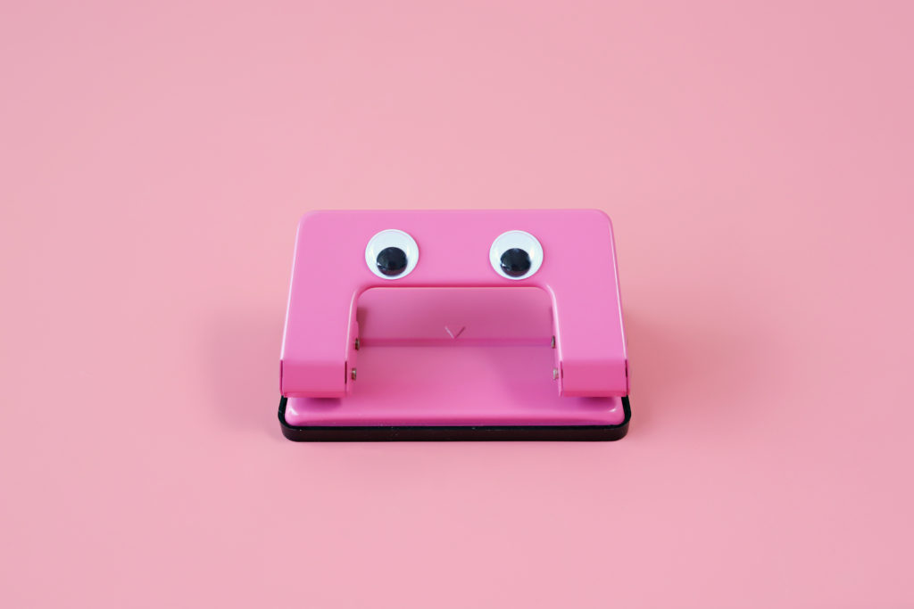 Close-Up Of Hole Puncher With Googly Eyes Against Pink Background