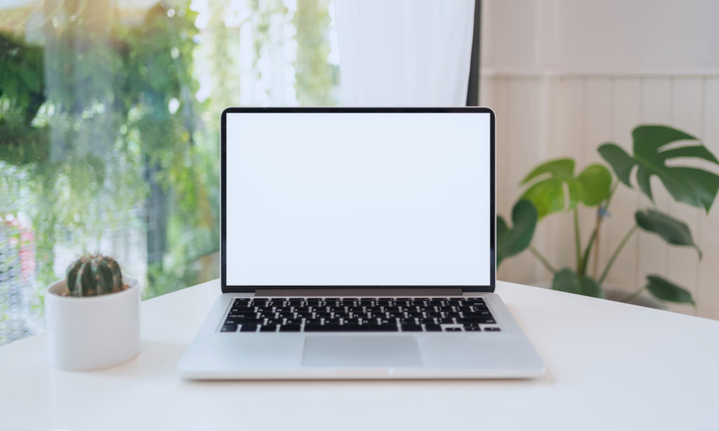 Laptop computer blank white screen on table in cafe background. Laptop with blank screen on table of coffee shop blur background.