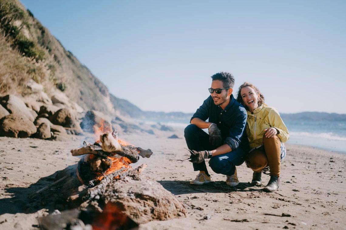 Mid adult couple enjoying campfire on beach in winter, Tokyo Bay