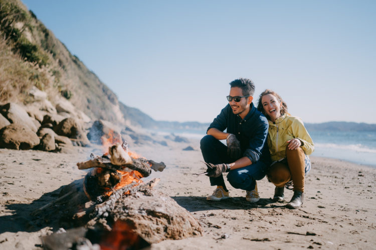 Mid adult couple enjoying campfire on beach in winter, Tokyo Bay