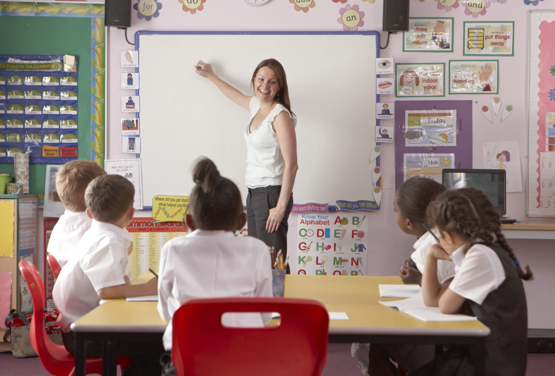 Teacher standing at a whiteboard teaching a class