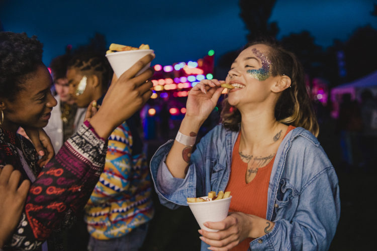 Small group of friends are sharing portions of chips at a festival.