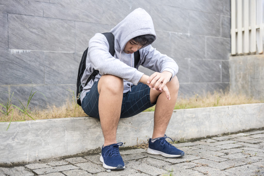 Teenage Boy Sitting looking sad
