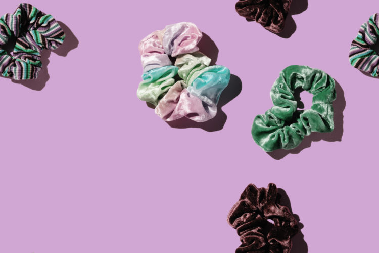 Colorful hair scrunchies over a pastel background with copy space on bottom left side. Flat lay of scrunchies on a pastel background.