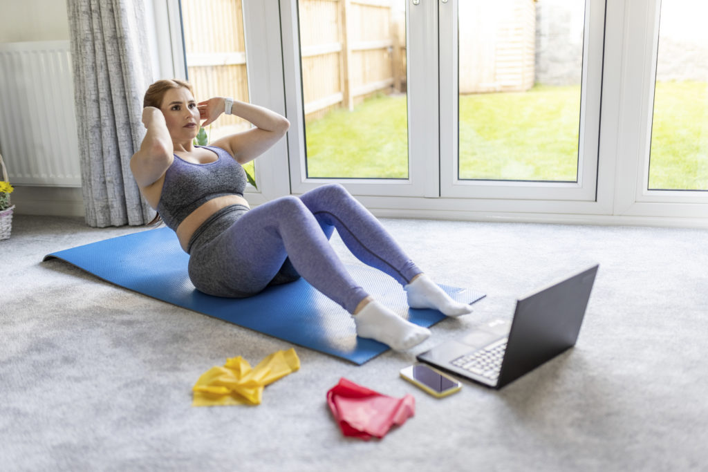 Mid adult woman practicing sit-ups while exercising at home