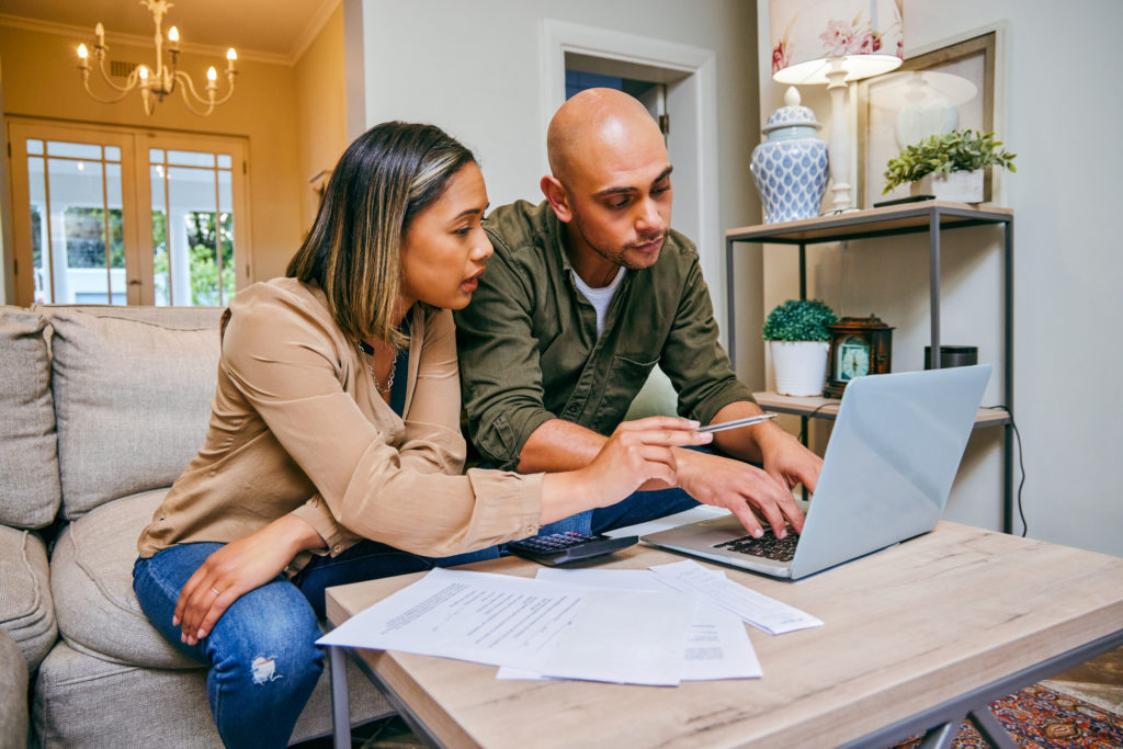 Shot of a young couple reviewing their finances while using their laptop