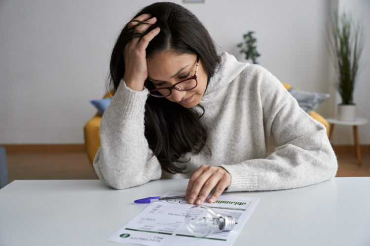 Woman looking worried while checking electricity bill at home. Electricity, finance, crisis and bills concept.