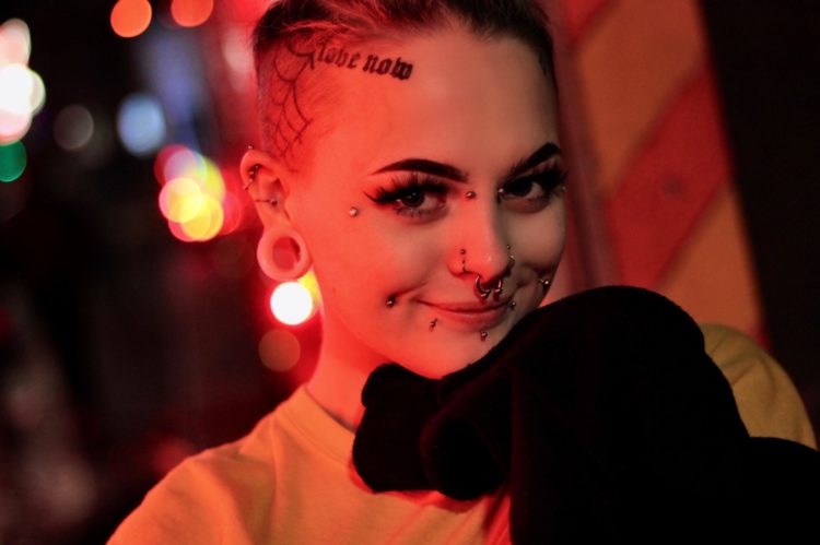 grayscale photo of smiling woman wearing beige crew-neck shirt piercings new piercing