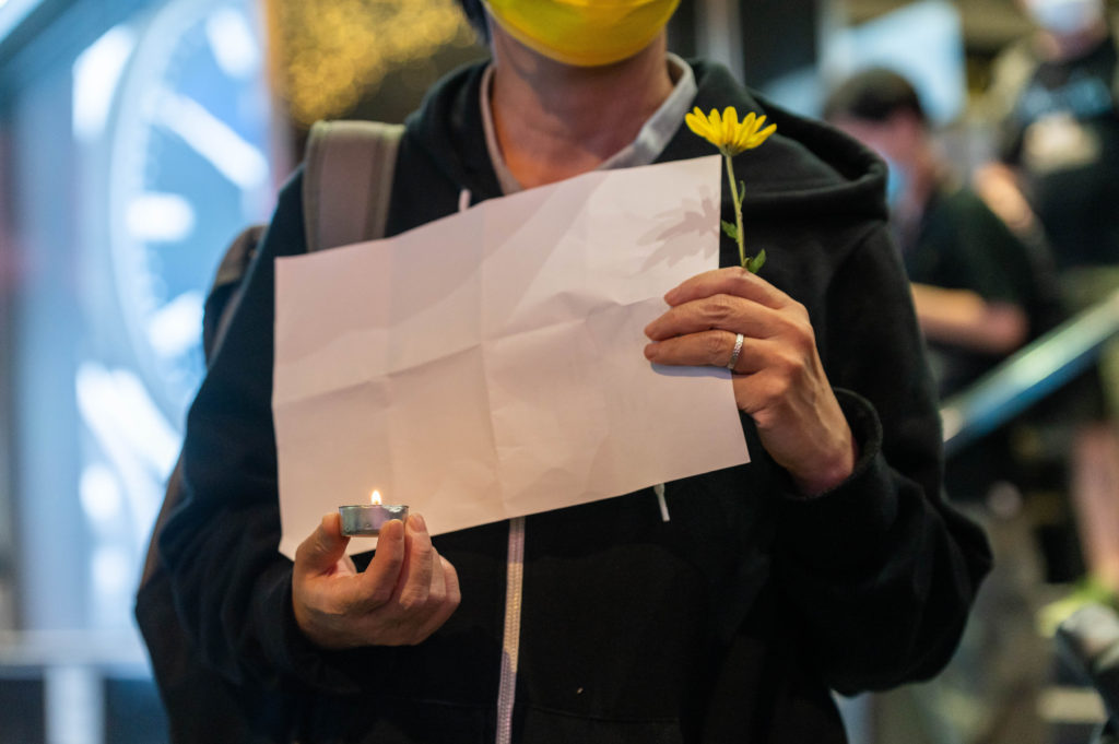 A protester holds up a blank piece of paper and a candle