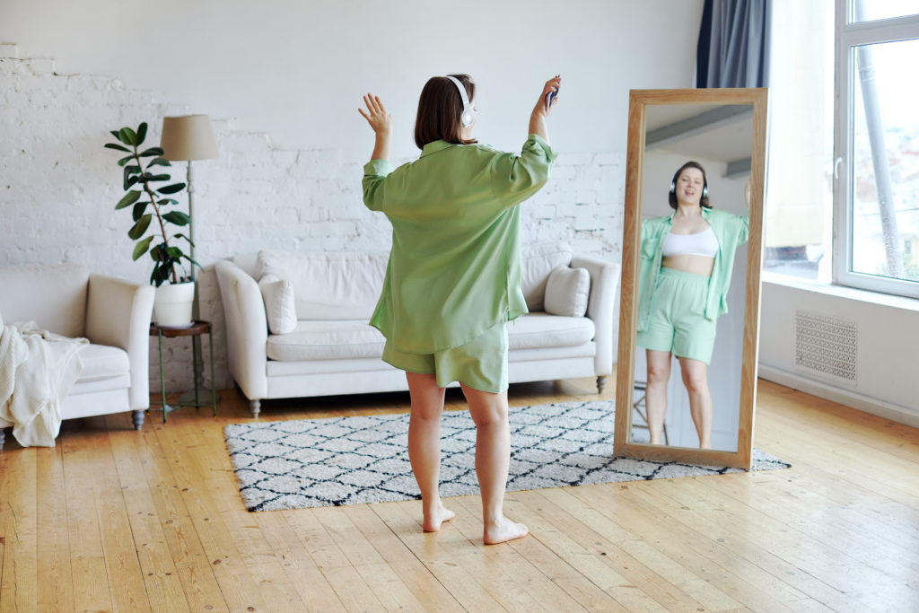 Plus size woman dancing standing barefoot in living room