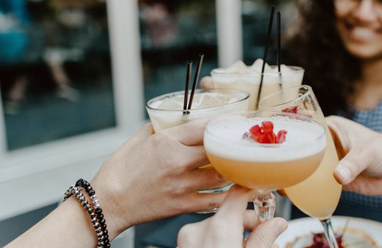 person holding filled drinking glasses with cocktails