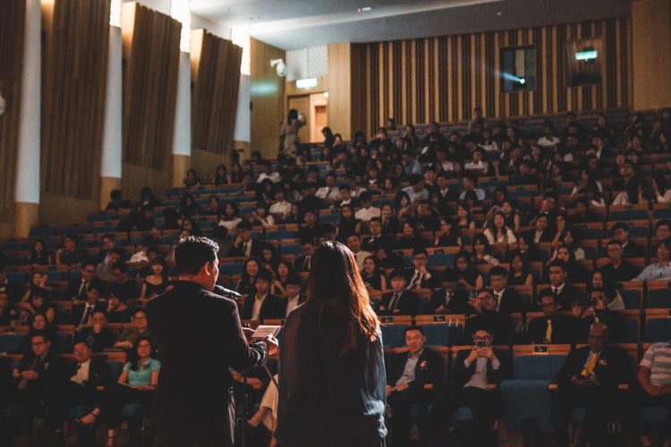 university lecturer delivering lesson to full lecture hall