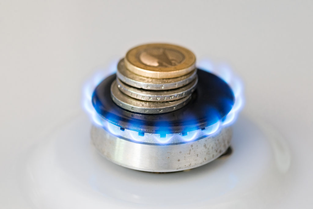 A lit gas burner burns money with a blue flame - Concept illustrating rising gas prices