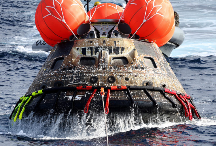 AT SEA, PACIFIC OCEAN - DECEMBER 11: NASA's Orion Capsule is drawn to the well deck of the U.S.S. Portland after it splashed down following a succe...