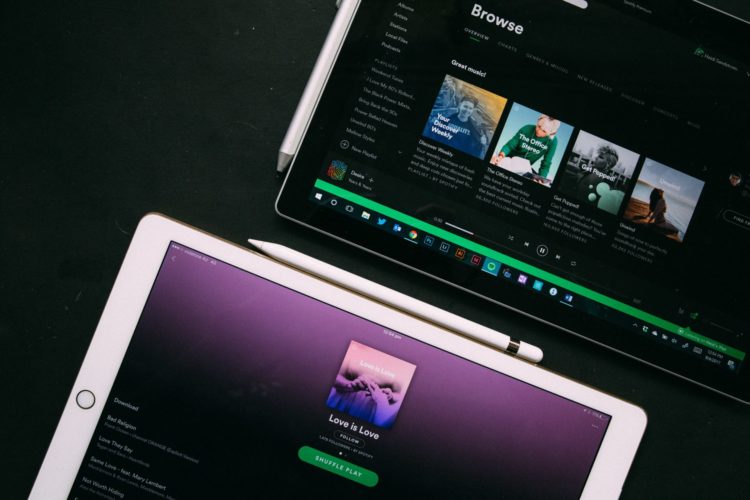 two white ipads displaying spotify page on black background