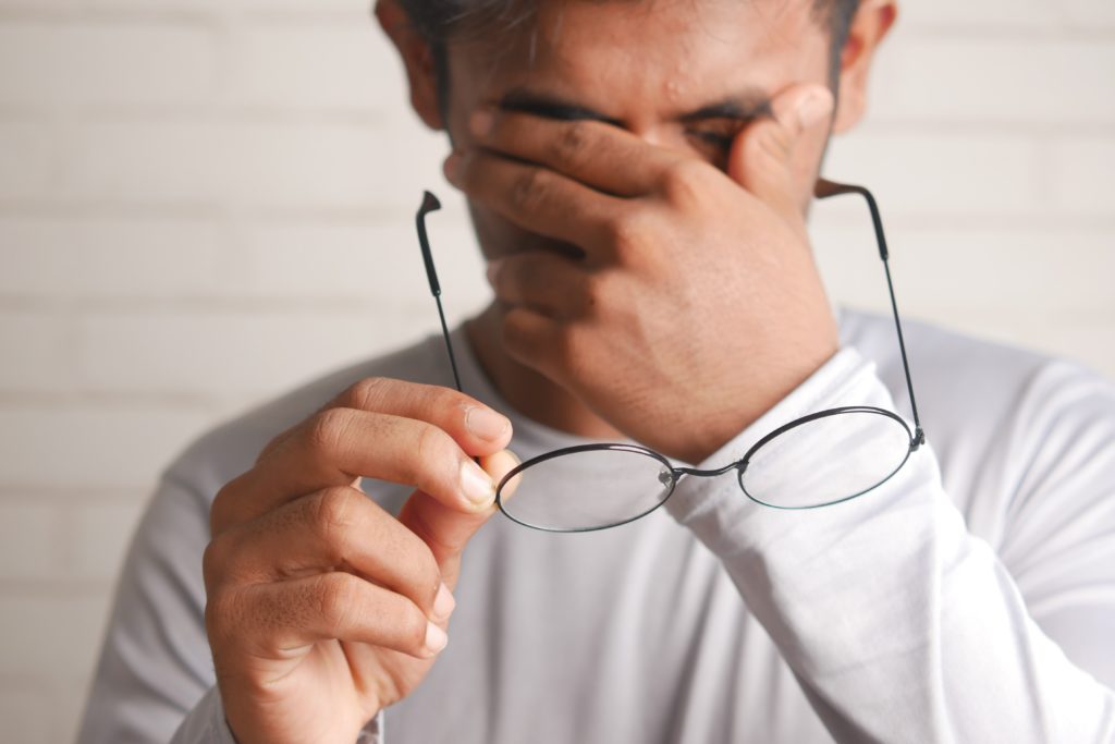 man removing glasses and rubbing eyes