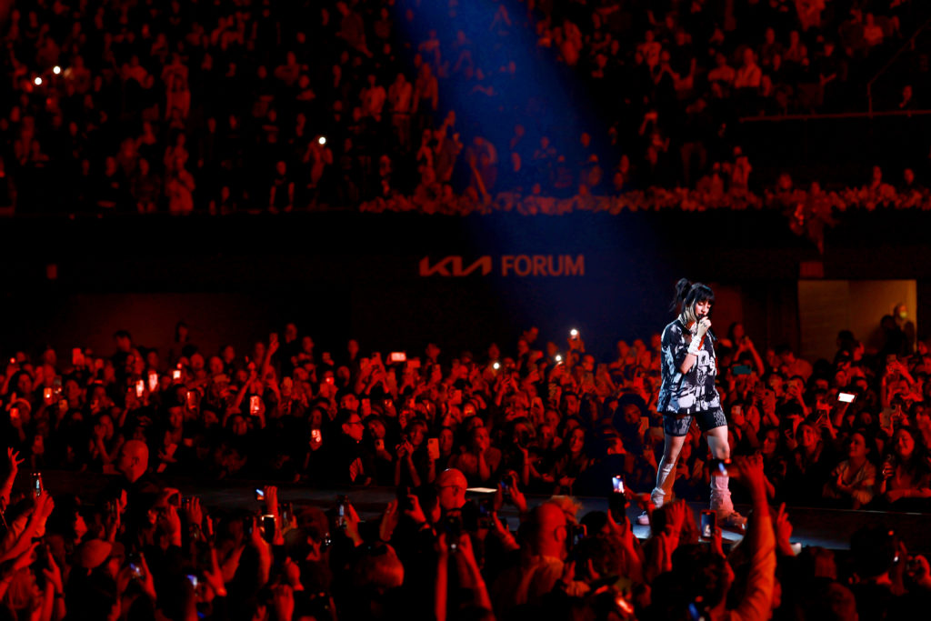 Billie Eilish performs in the middle of a crowd basked in a deep red light