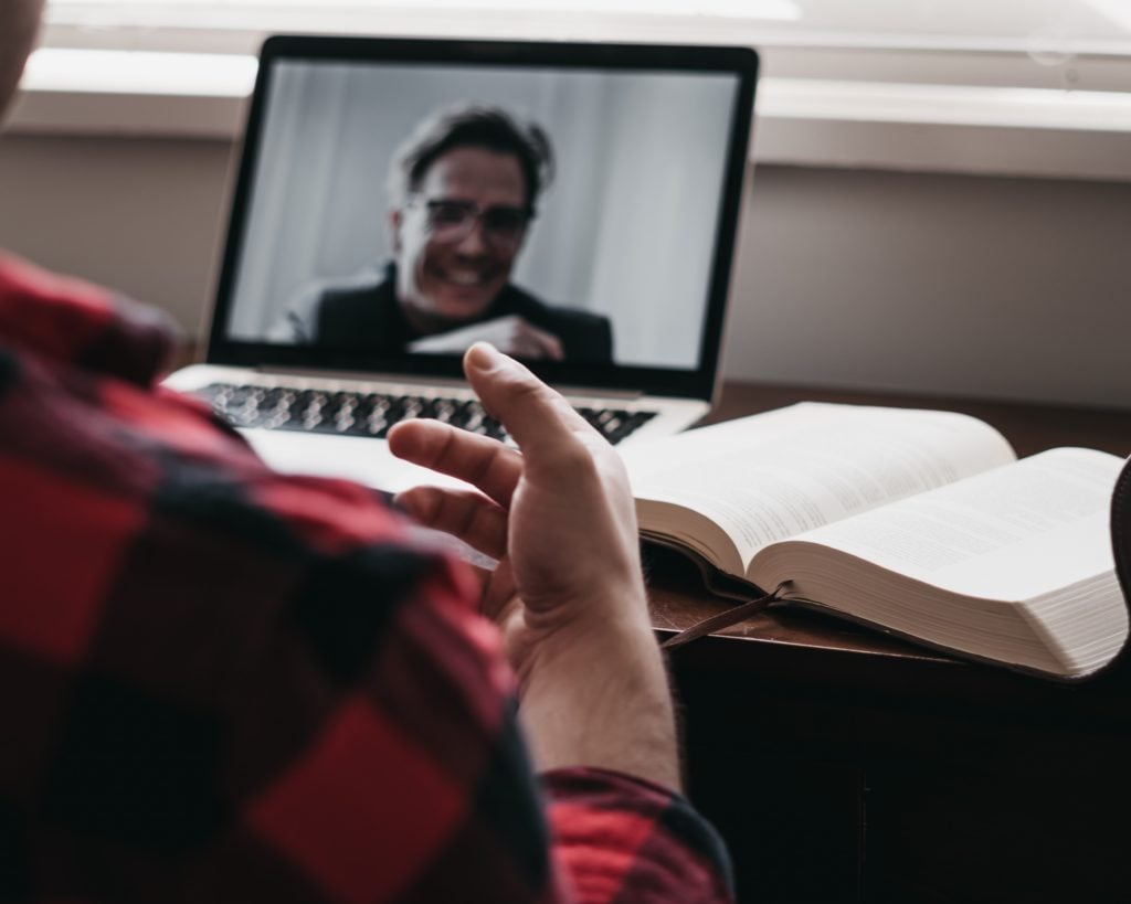person in red and black plaid long sleeve shirt talking to man on black laptop computer