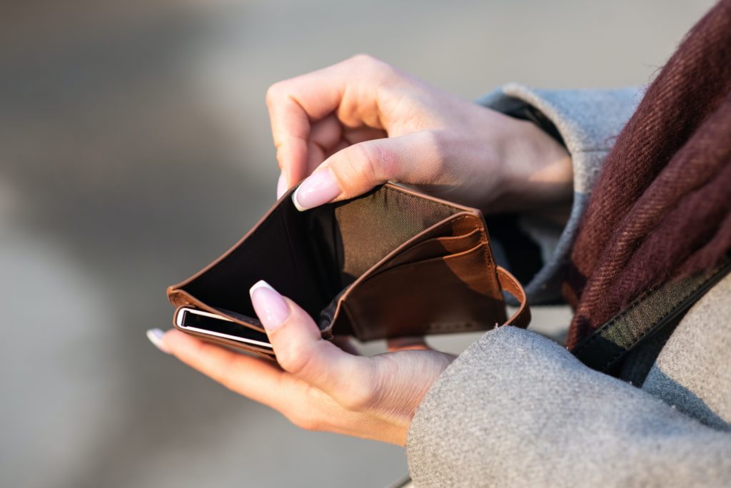 woman holding brown wallet open with no money inside