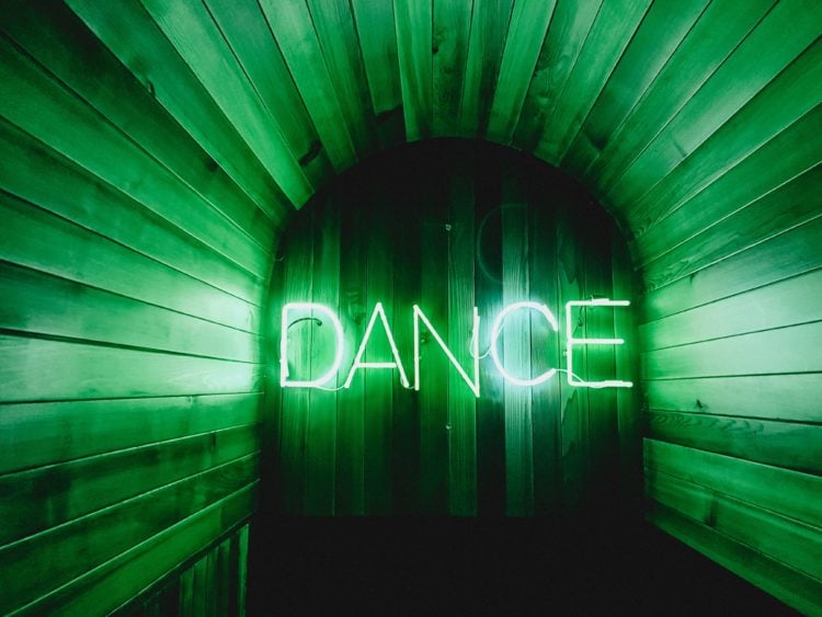 wooden hut with large green neon light reading dance